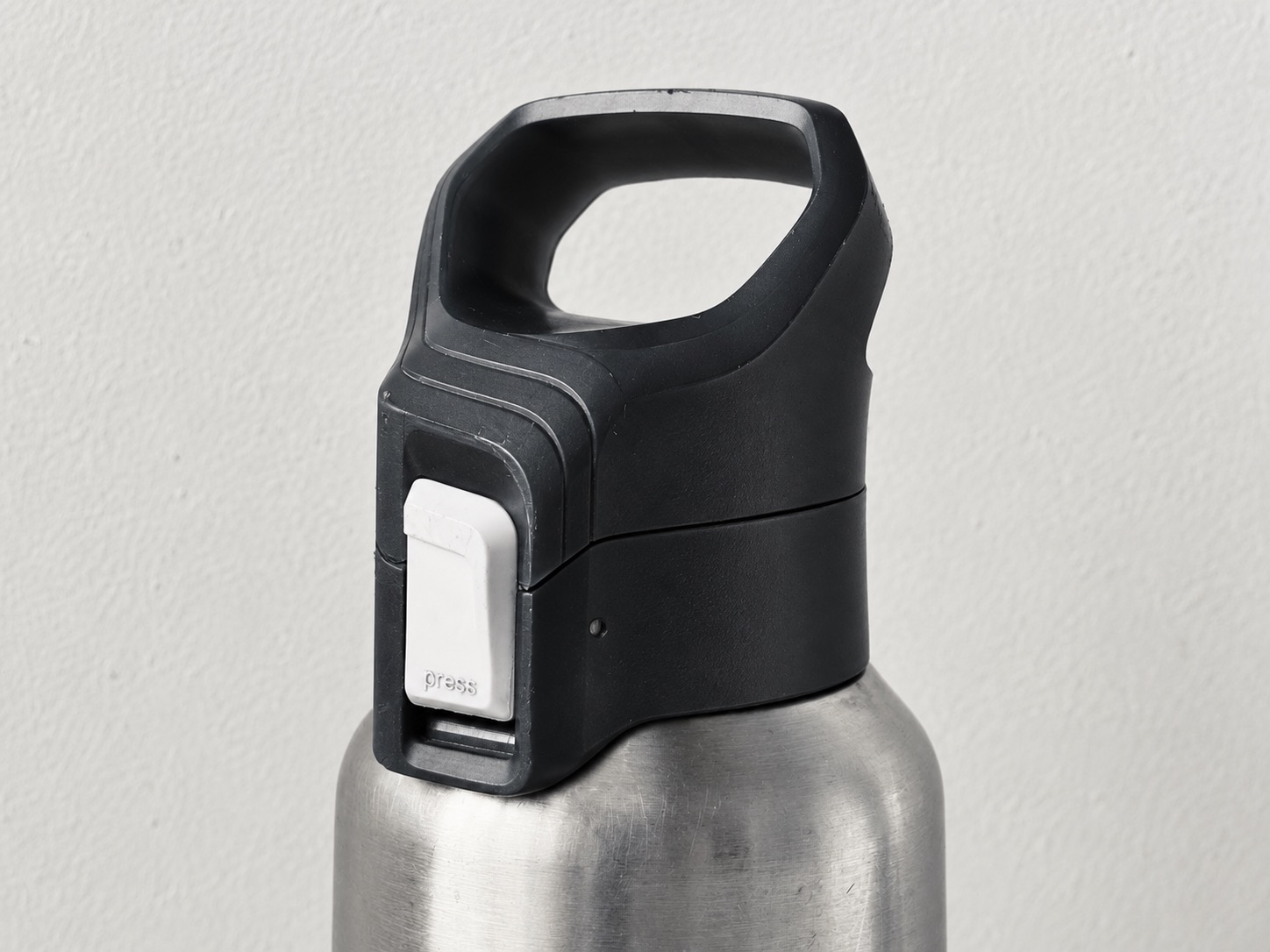 Close view of a bottle lid button, protective loop and closed drinking cap