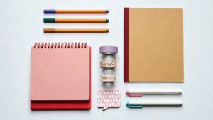 Overhead arrangement of notebooks, pens, tape rolls and a note pad