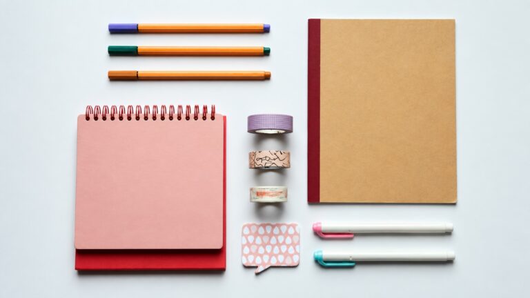 Overhead arrangement of notebooks, pens, tape rolls and a note pad