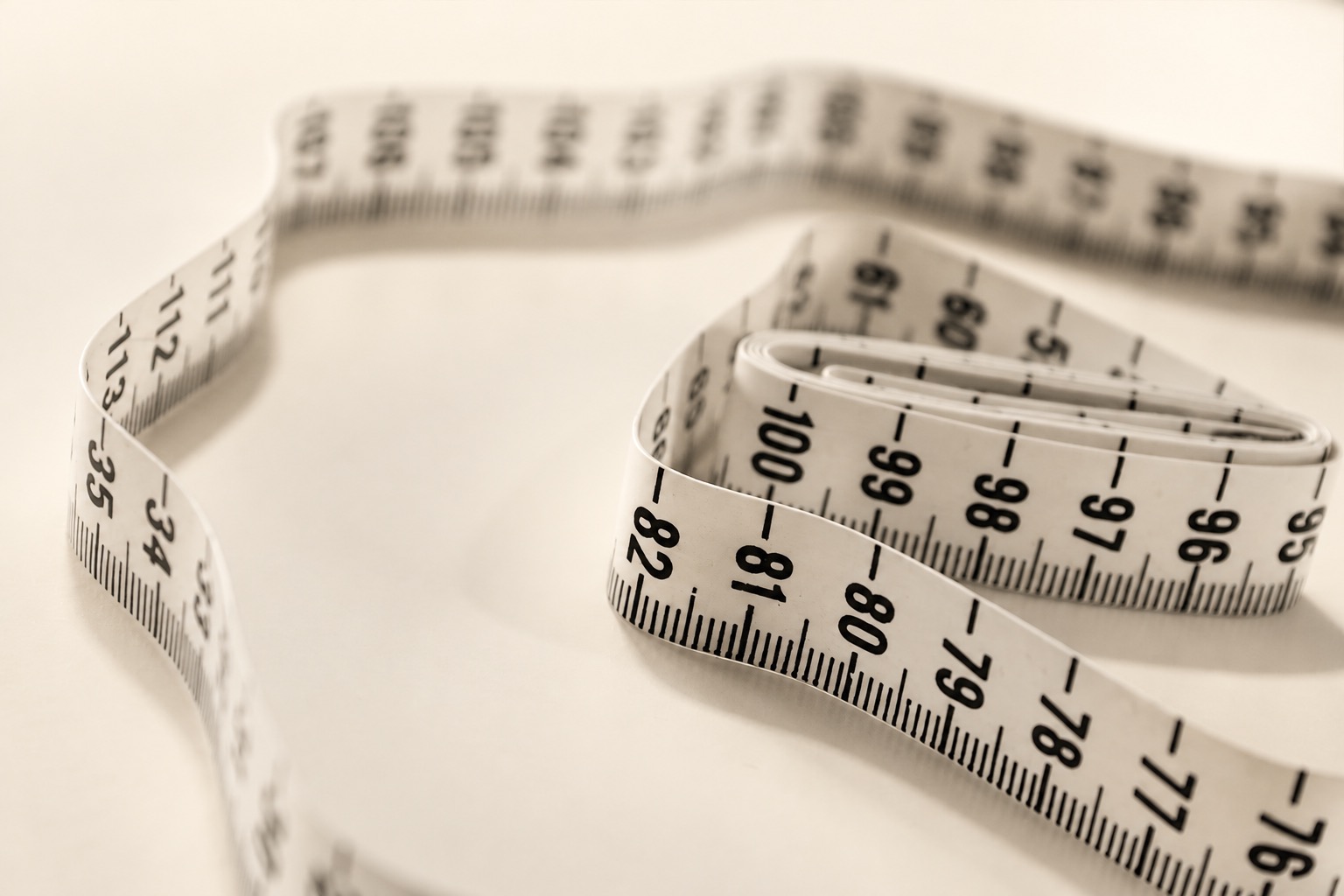 Close view of the numbered scale on a coiled flexible measuring tape
