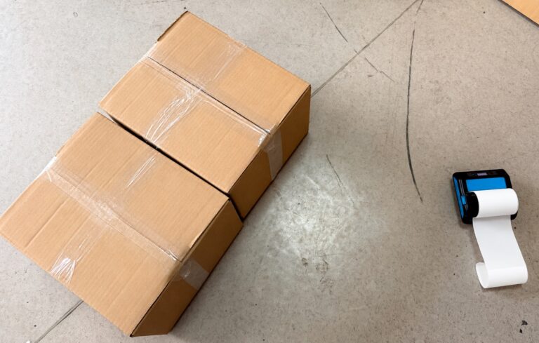 Two taped cartons beside a portable label printer illustrating dropshipping duplicate orders