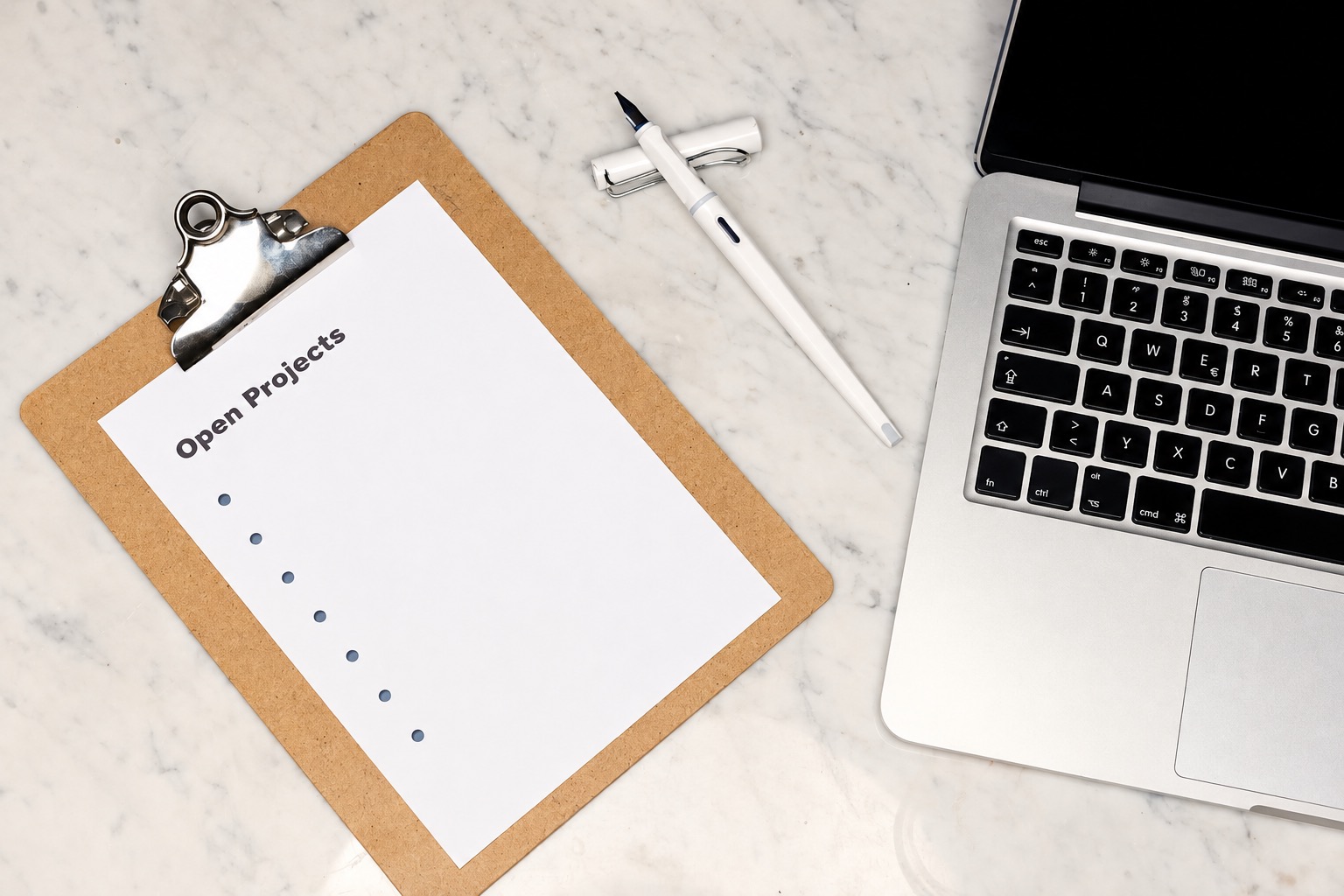 Blank project list on a clipboard beside a laptop and pen