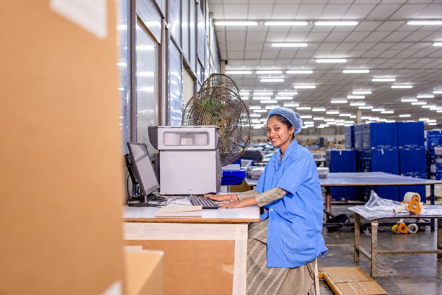 Worker at a computer beside packing materials illustrating order work before carrier handover