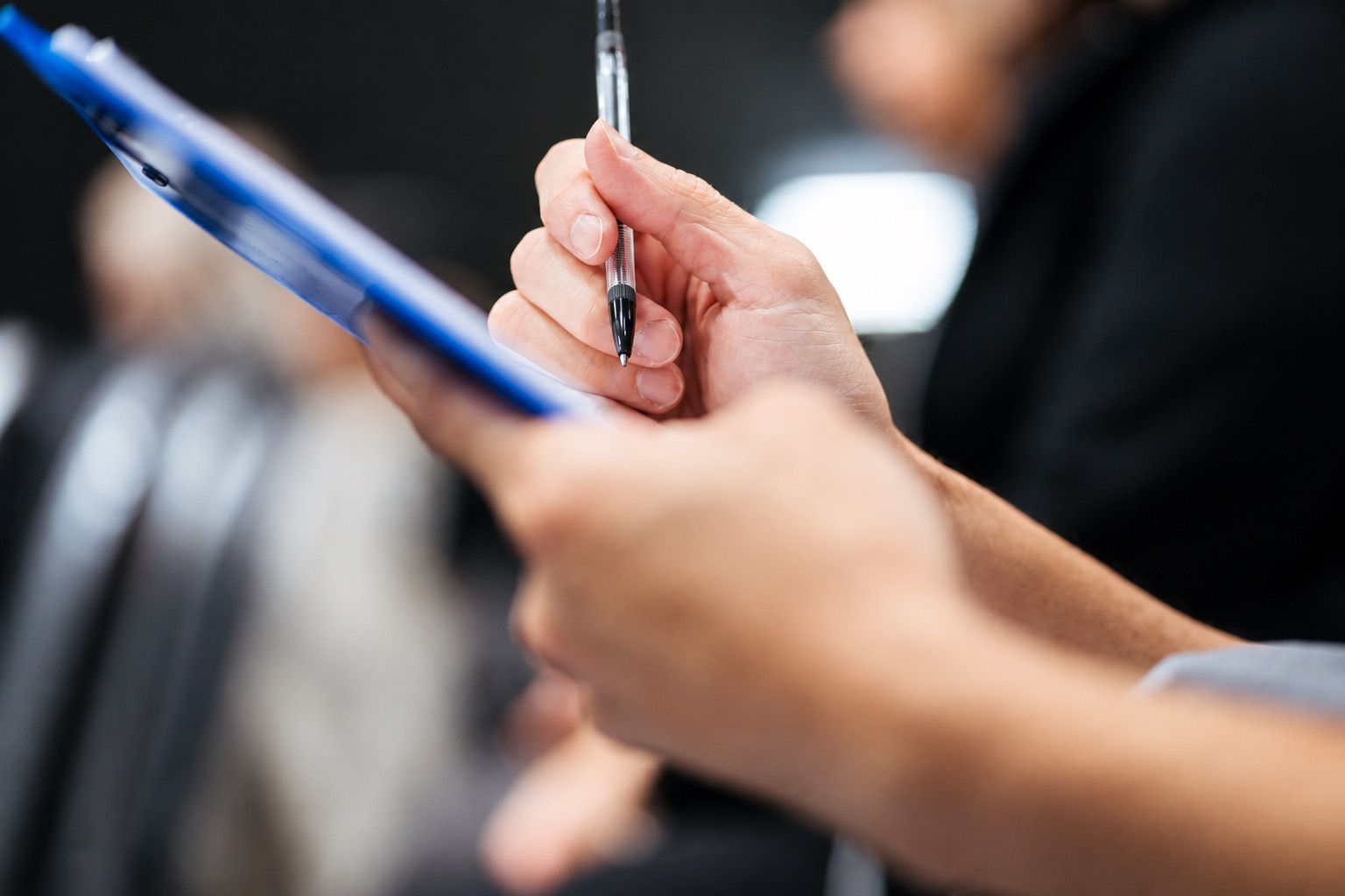 Hands writing on a clipboard during a review of dropshipping order holds