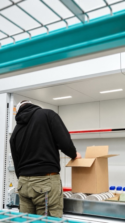 Worker preparing a carton at a storage station