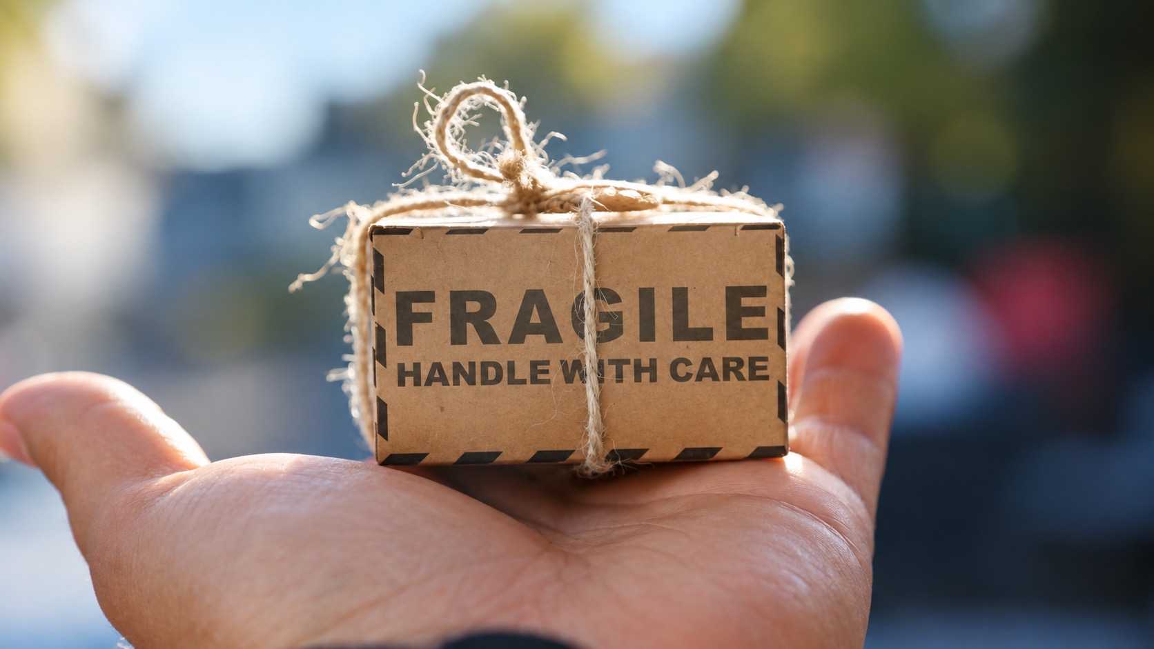 Small parcel marked Fragile on an open palm, illustrating shipping damage precautions
