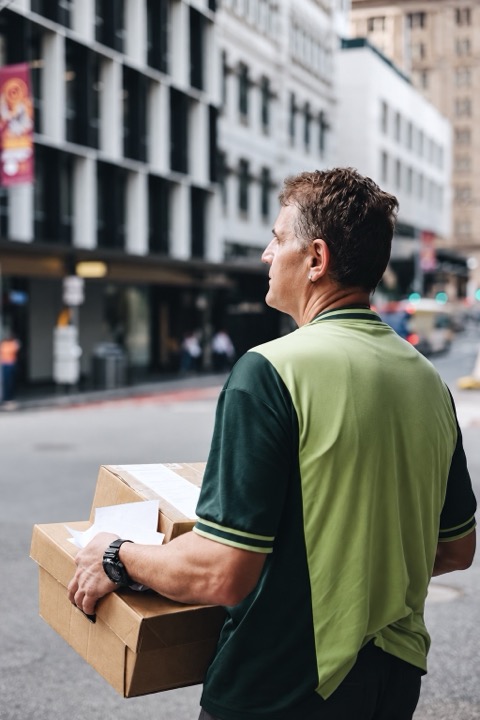 Courier holding two cartons on a city street