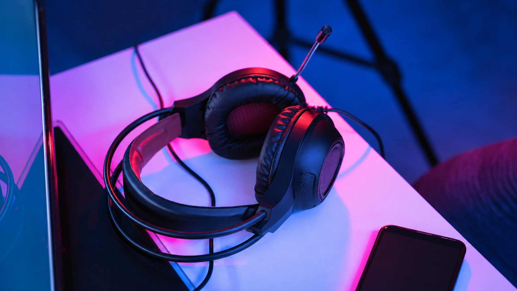 Wired headset on a desk with a separate phone and screen edge