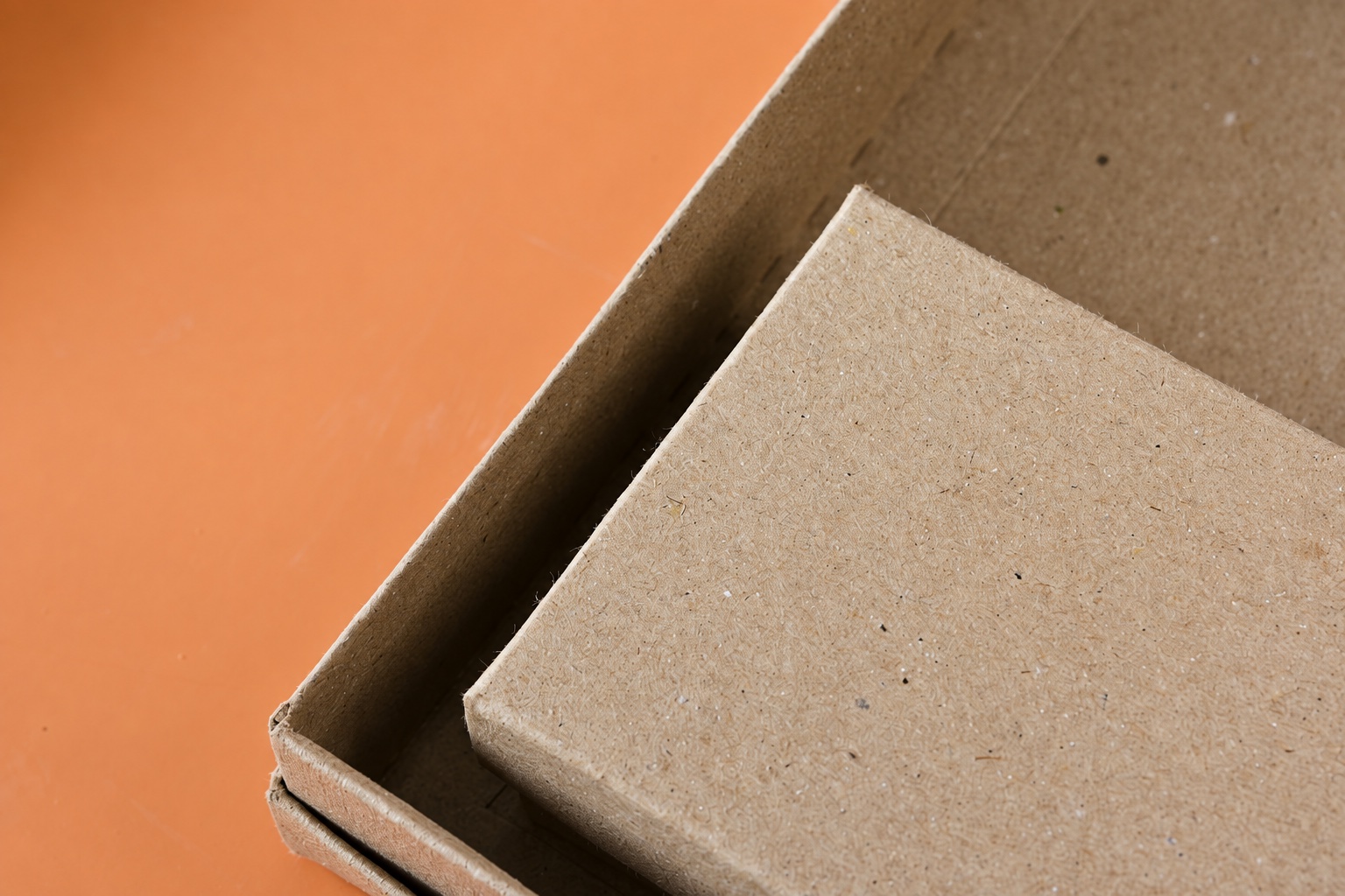 Close-up of inner and outer kraft board edges with a visible gap on an orange surface