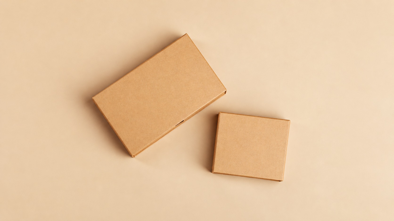Two closed kraft retail boxes of different sizes on a beige surface