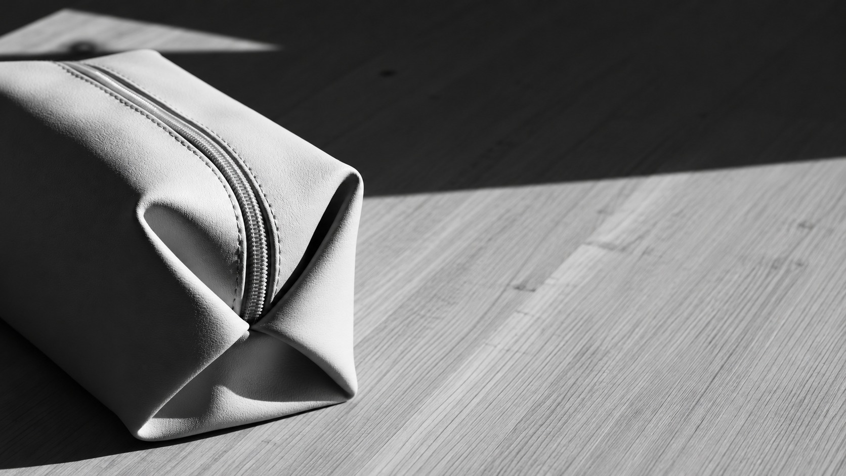 Close detail of a monochrome pouch zipper and folded side gusset