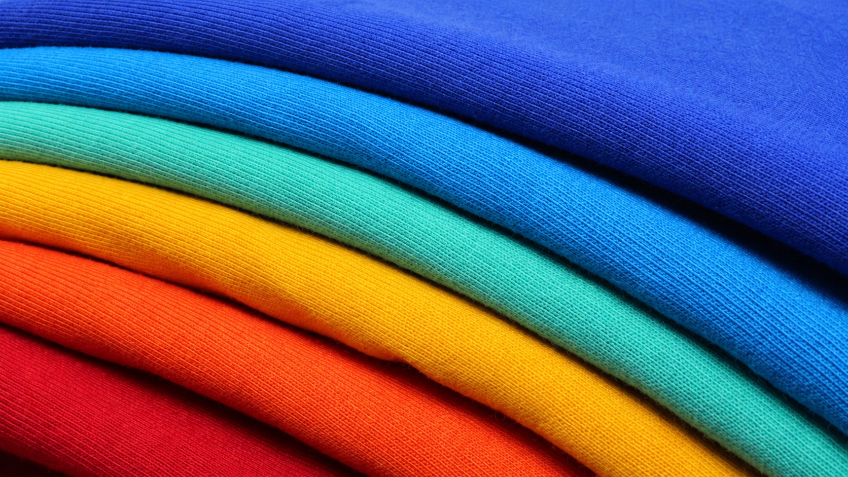 Close view of six folded garment edges in blue cyan mint yellow orange and red