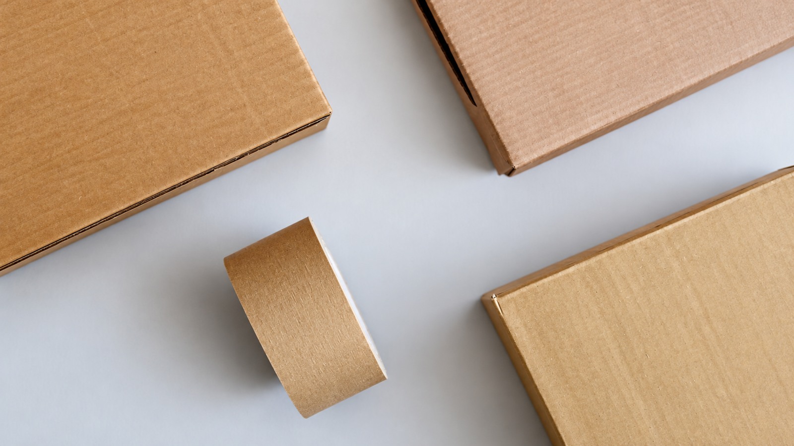 Four closed kraft boxes of different sizes on a pale surface