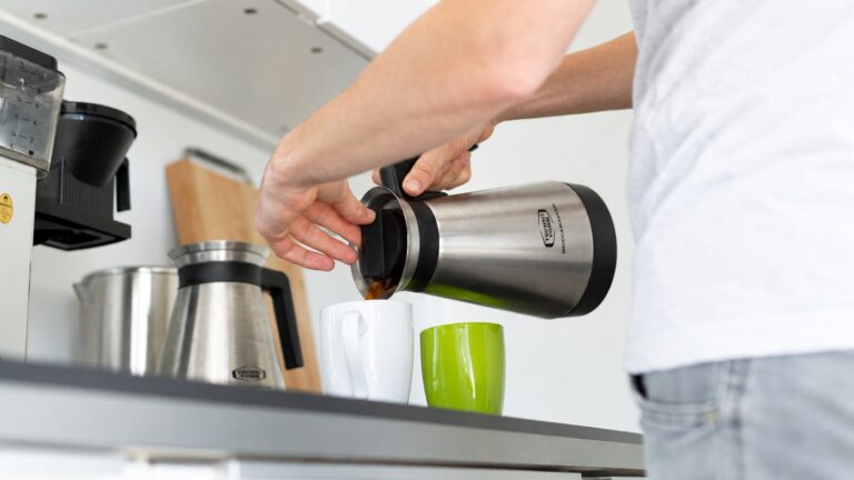 Hands supporting a lid and pouring into a cup, illustrating handling for a product demo video