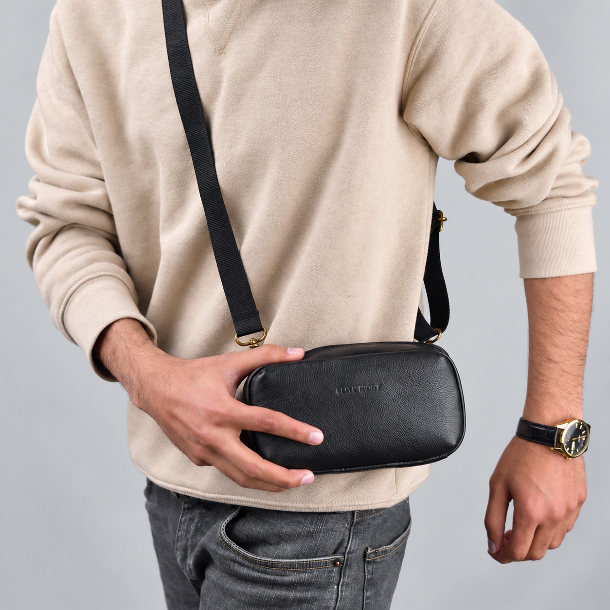 Person wearing a black bag with a long strap while supporting the bag with one hand