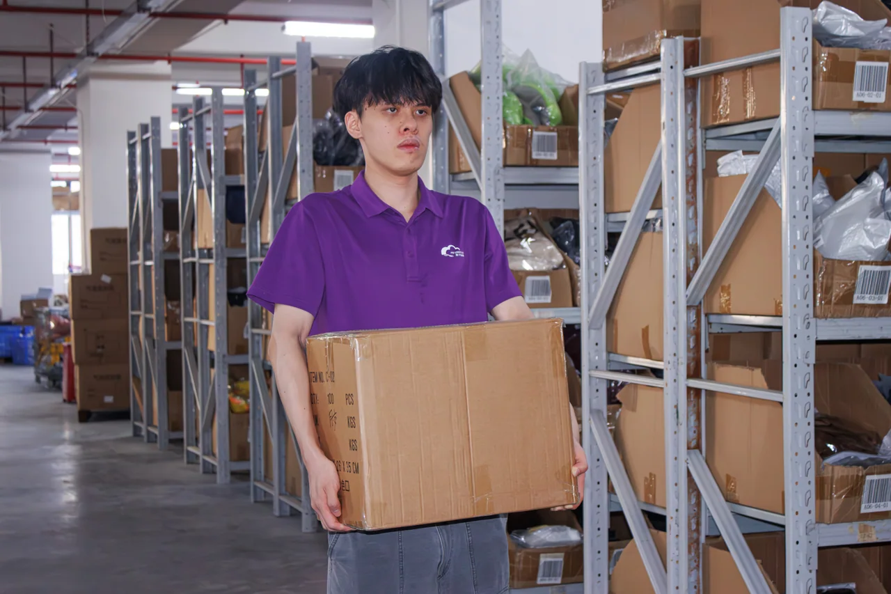 A cardboard carton being carried beside warehouse storage racks