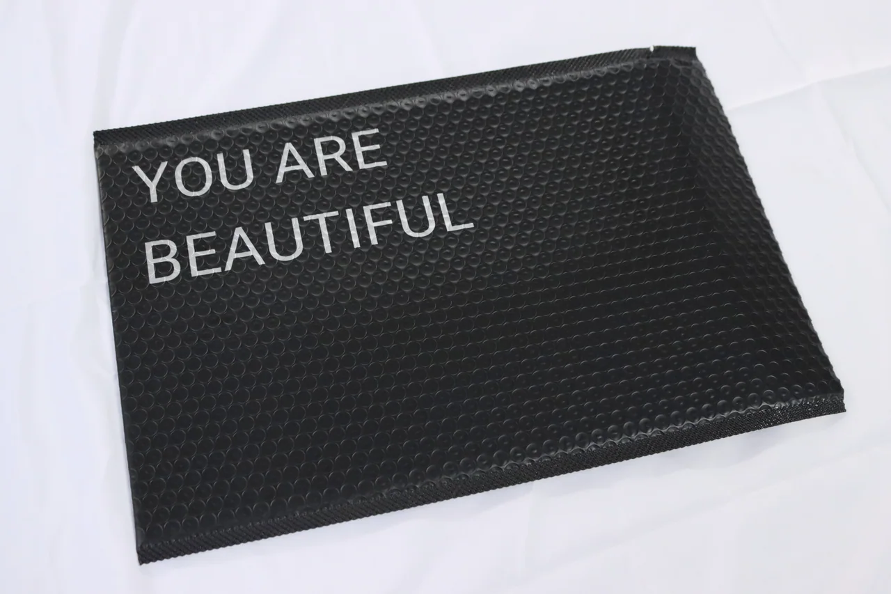 Black padded bubble mailer with white lettering on a white surface