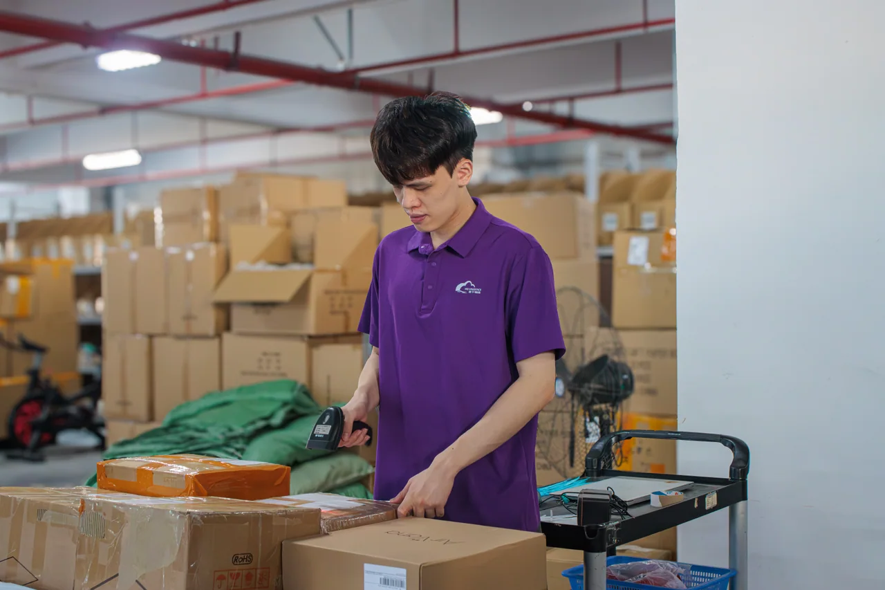 Warehouse worker handling cardboard cartons at a packing station