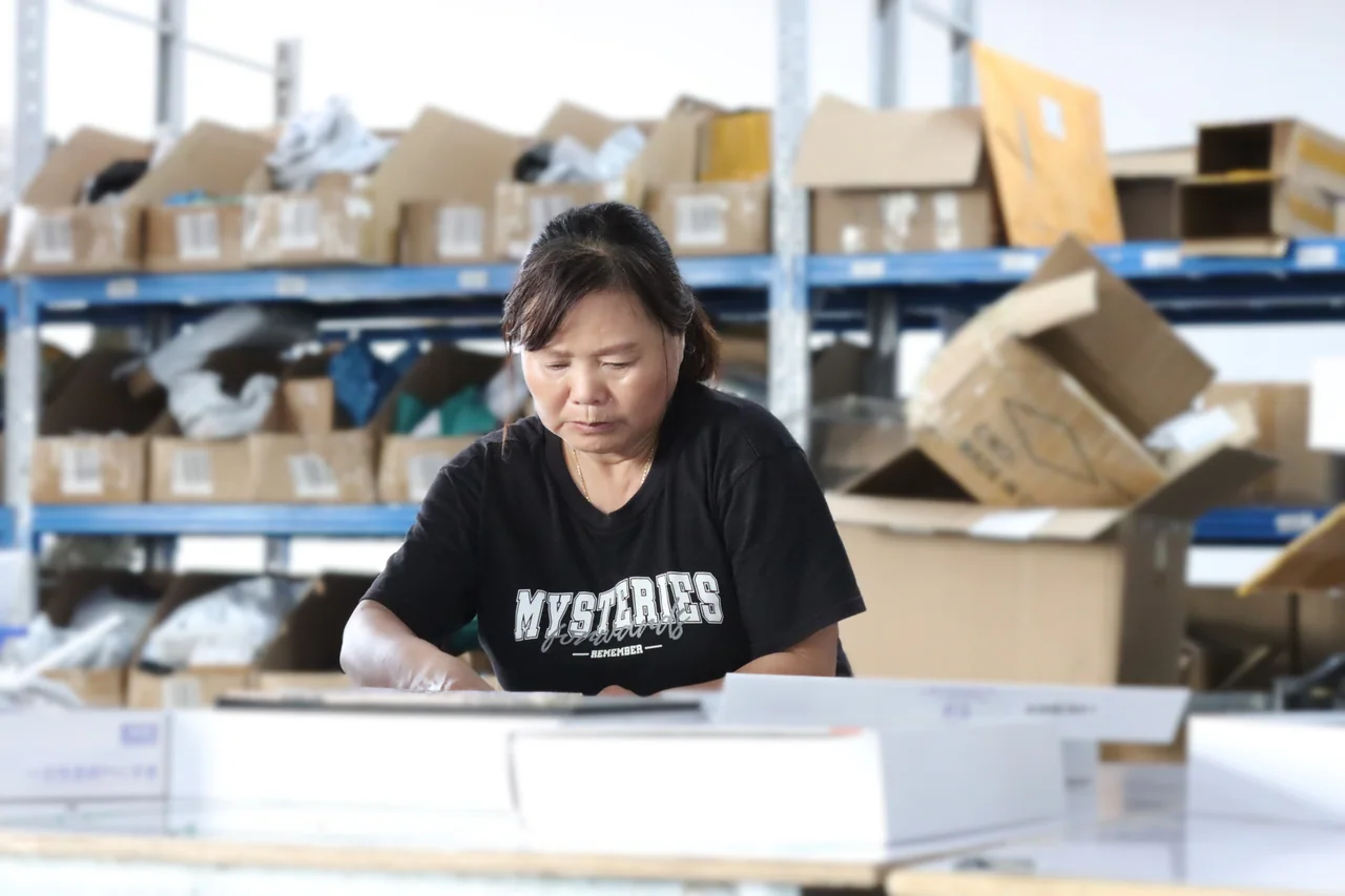 Warehouse worker preparing boxed items at a packing worktable